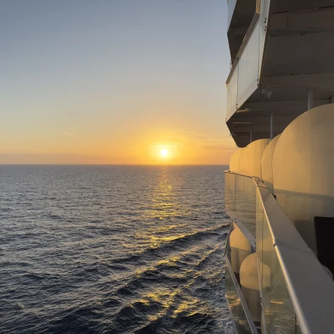 A side view of Wonder of the Seas off the Florida Coast with a beautiful sunset and the ocean waters in the distance. 
