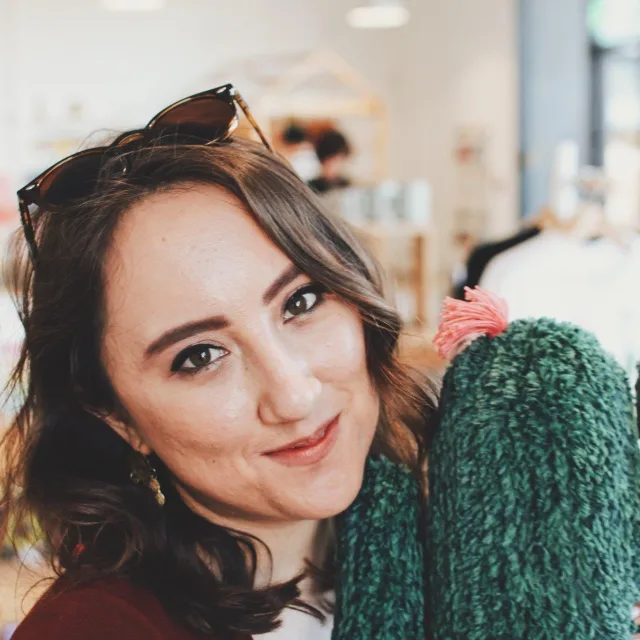 Travel Advisor Erika Pontius with a green sweater and sunglasses on her head.