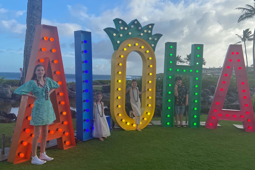 A woman and two kids standing near colorful AIOHA landmark.