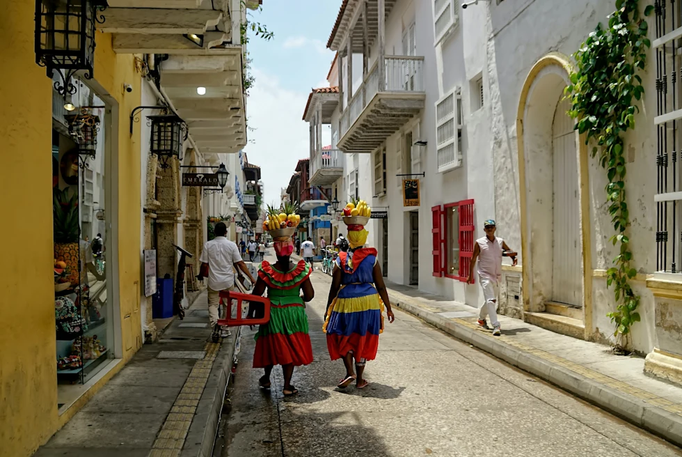 People walking on road between concrete houses during daytime.