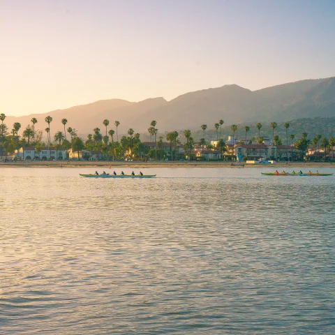 boats in body of water with mountains in the background during sunset