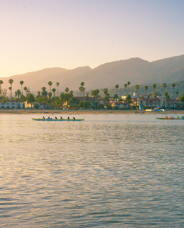 boats in body of water with mountains in the background during sunset