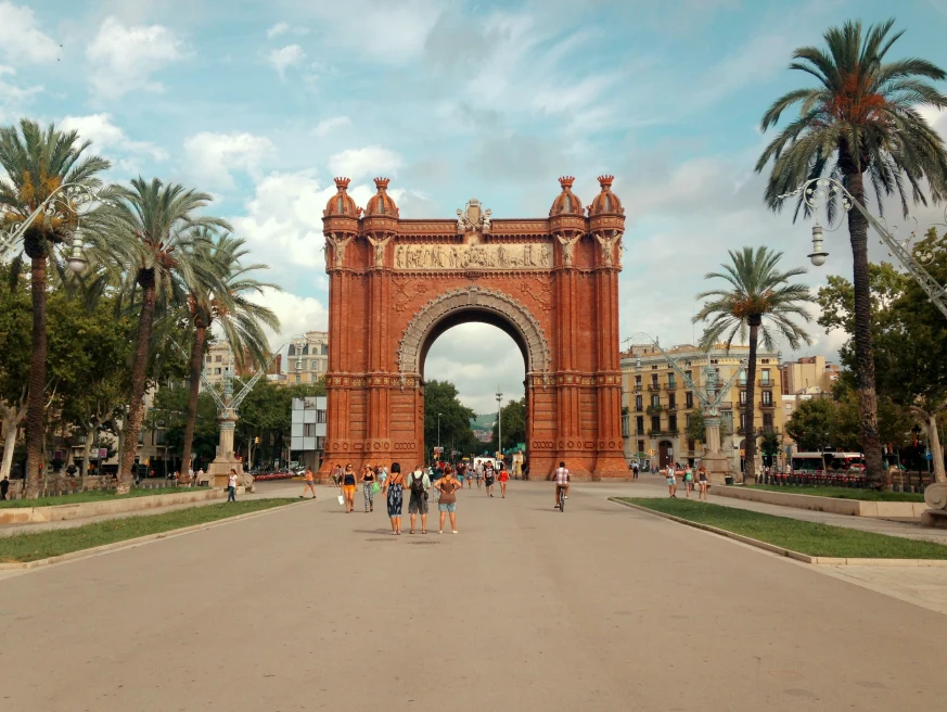 large arch over street next to palm trees during daytime