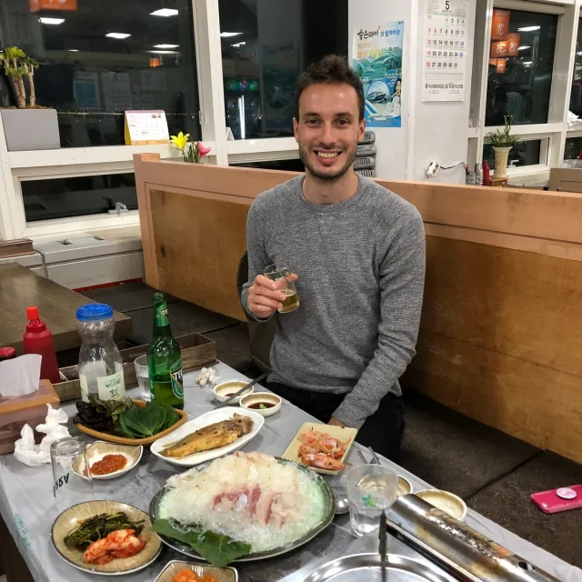 Travel Advisor Jack Fischl in a grey sweater in front of a hot pot meal.