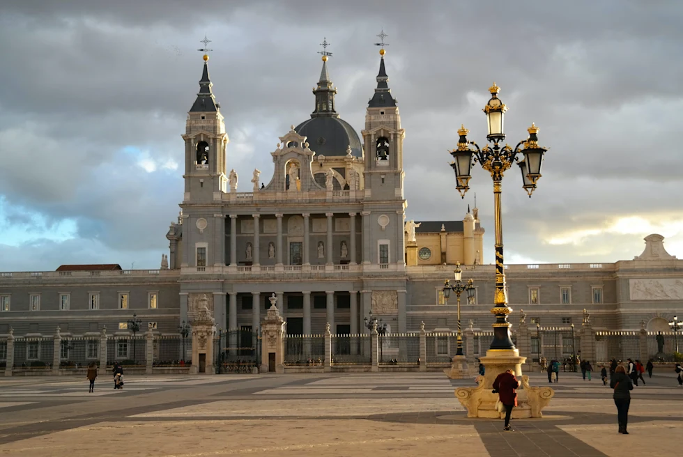 People walking near large building with cloudy skies during daytime