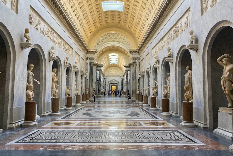 hall of a museum with ornate tile and sculptures lining the walls