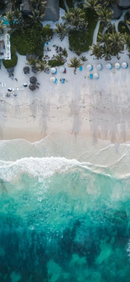 Birdseye view of clear blue ocean waters and white sands on a beachside resort in Tulum, Mexico in Central America.