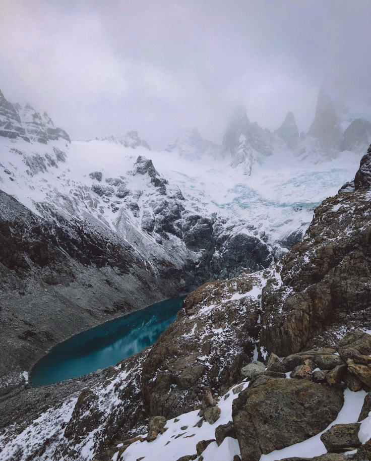 Snow-covered mountains and blue water on a cloudy day