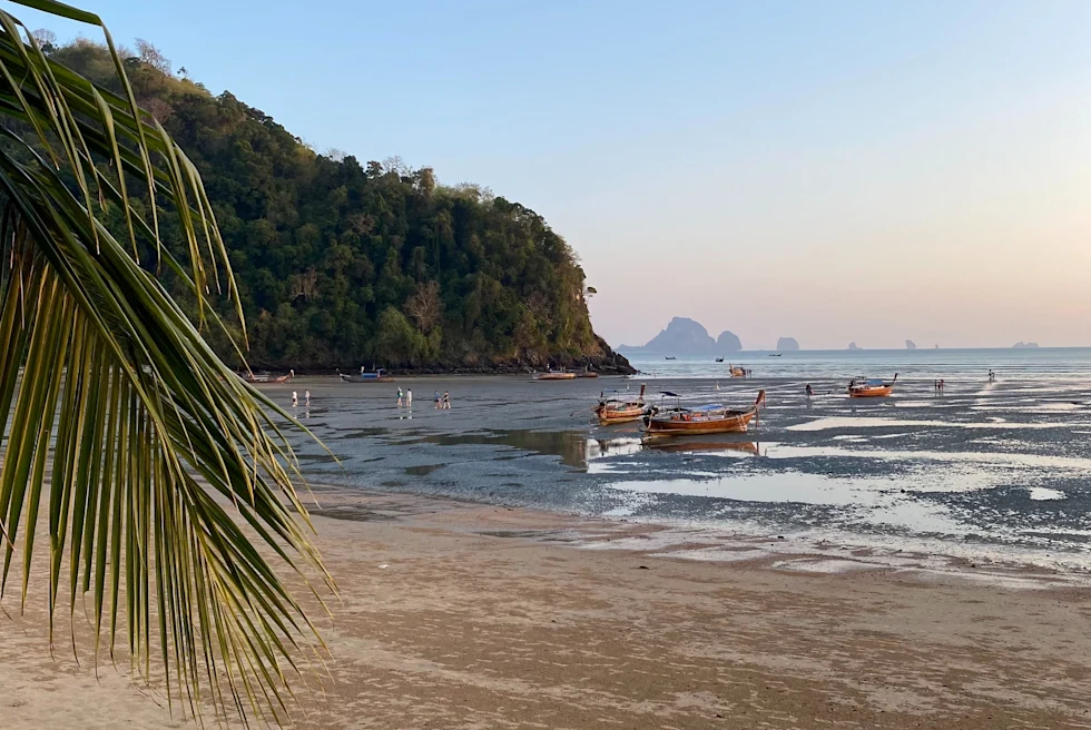 A beautiful island with boats on the water in Thailand.