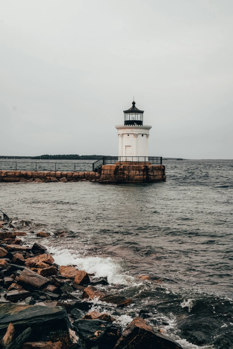 white lighthouse next to body of water