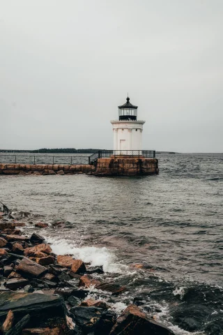 white lighthouse next to body of water