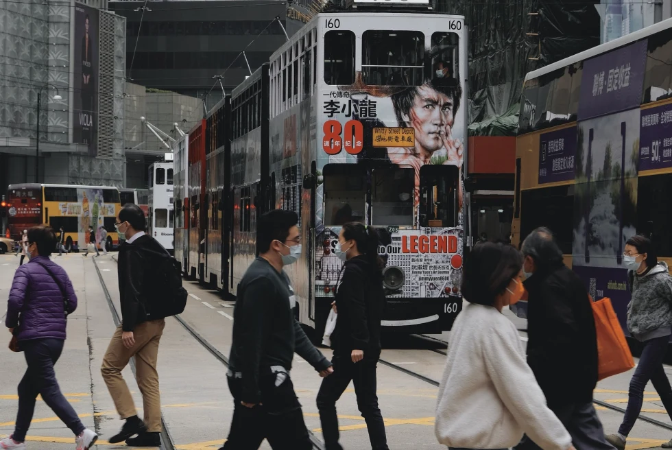 People walking on streets with double decker buses. 