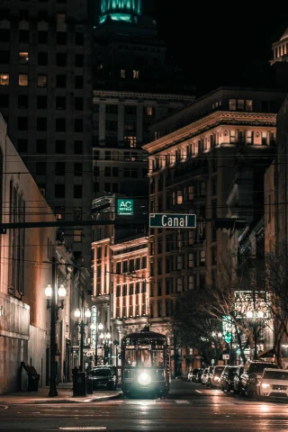 Night view of a street in New Orleans with 4-Star hotels and illuminated buildings, street lamps and a tram.