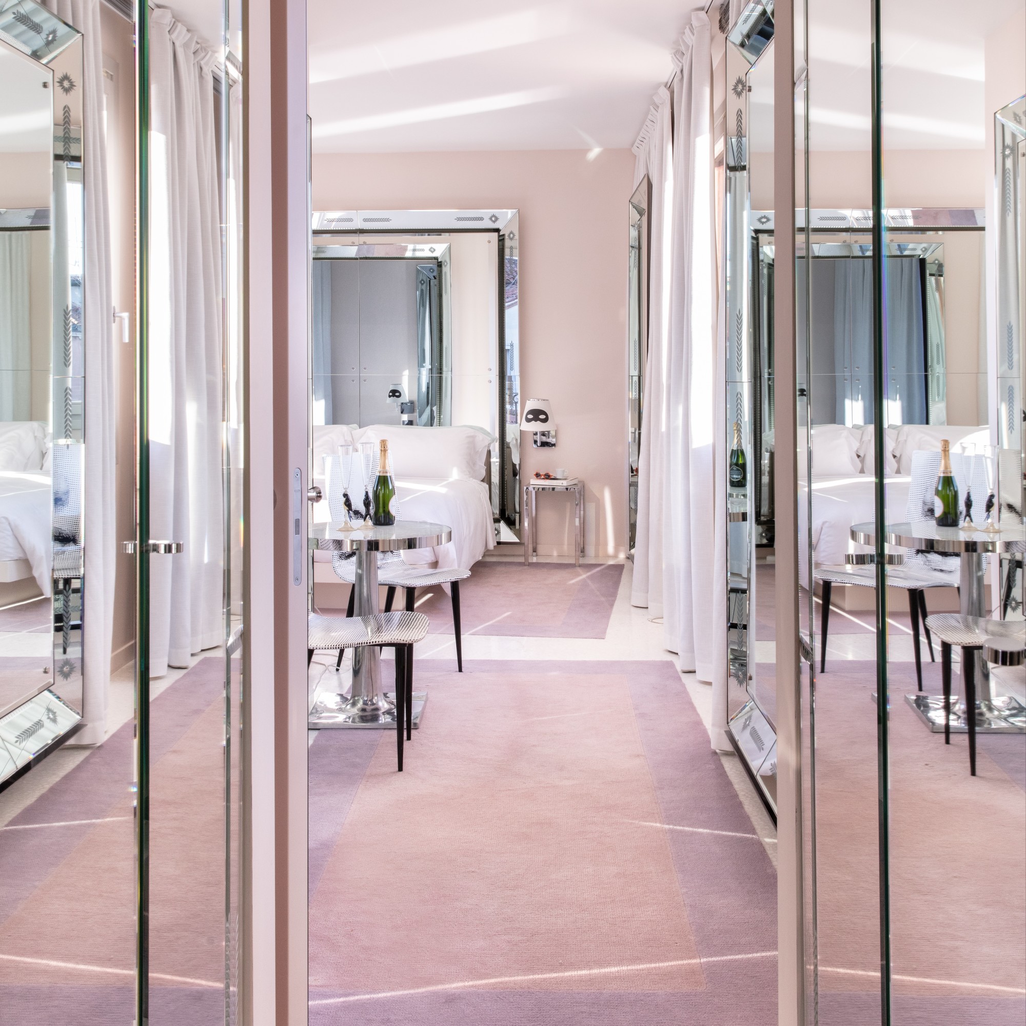 a mirrored hallway leading into a plush hotel room