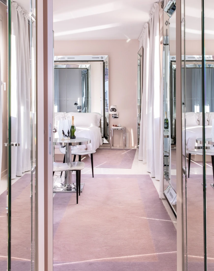 a mirrored hallway leading into a plush hotel room
