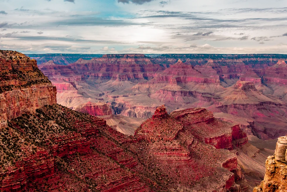 Expansive canyon with red rocks and a cloudy sky