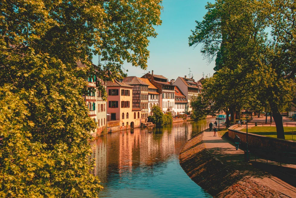 Canal lined with traditional building on a warmly lit day in Strasbourg, France. 
