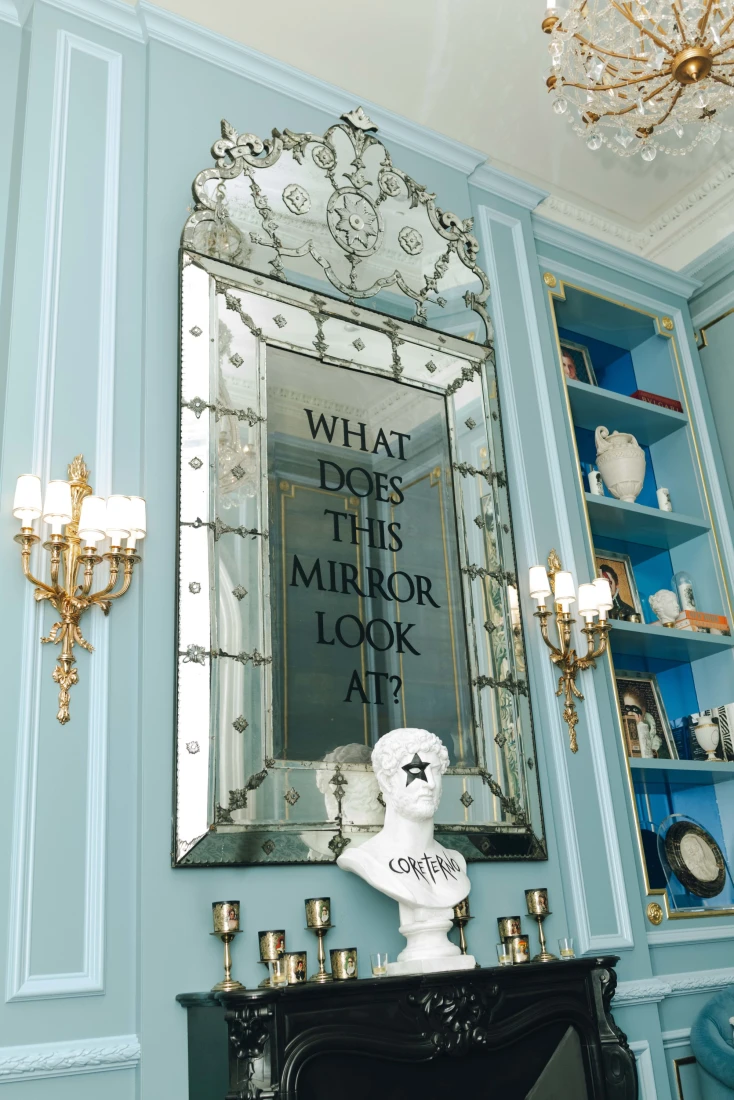 A mirror on a blue wall with writing on it