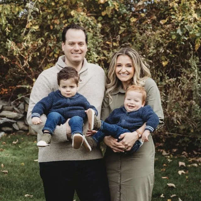 Melissa Schwartz smiling with her husband, each holding two young boys in their arms