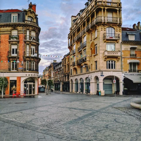 a cobblestone plaza leads to a street in a historic town in the afternoon