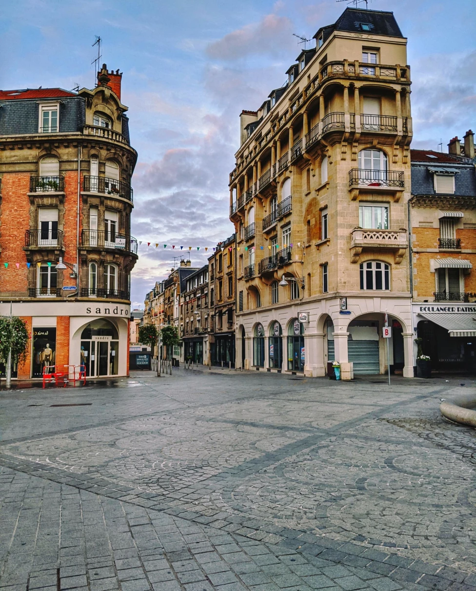 a cobblestone plaza leads to a street in a historic town in the afternoon