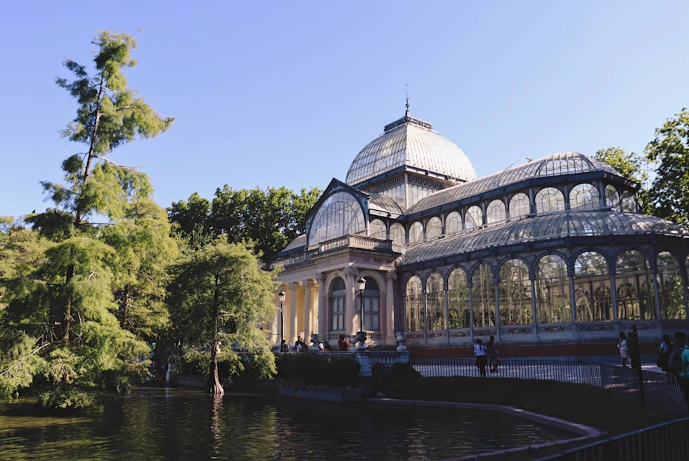 park with a large glass window building on a small pond with trees