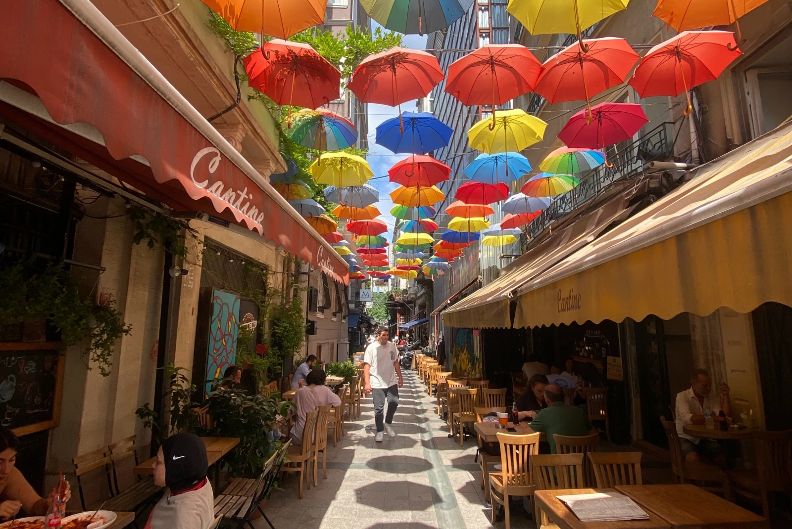 colorful umbrellas over an alley with tables and chairs