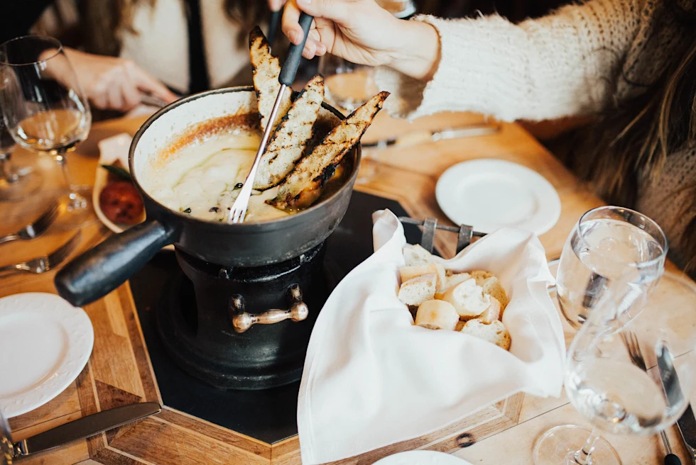 bread dipped in cheese over a large pot
