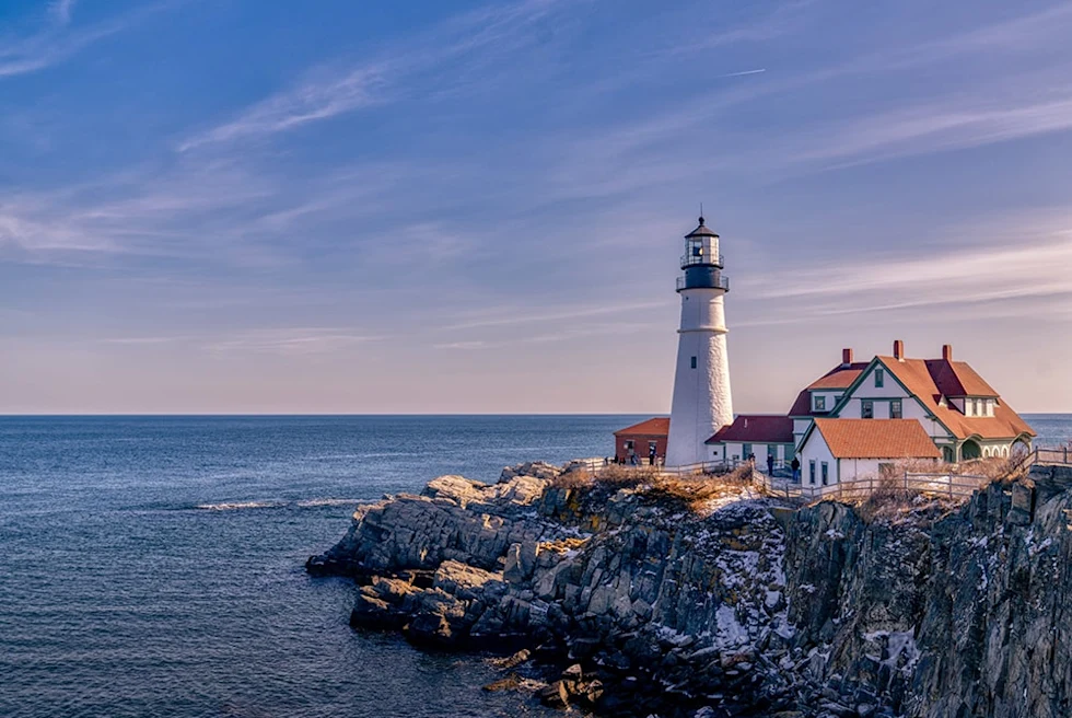 lighthouse next to body of water during sunset