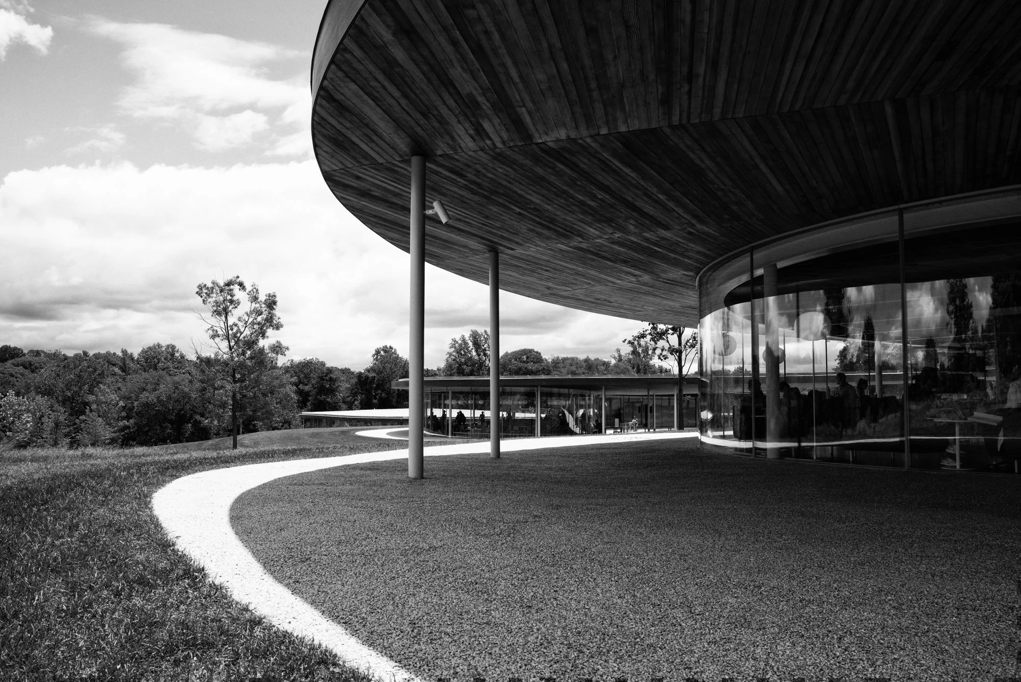 Greyscale picture of a park with a circular building and covered area. 