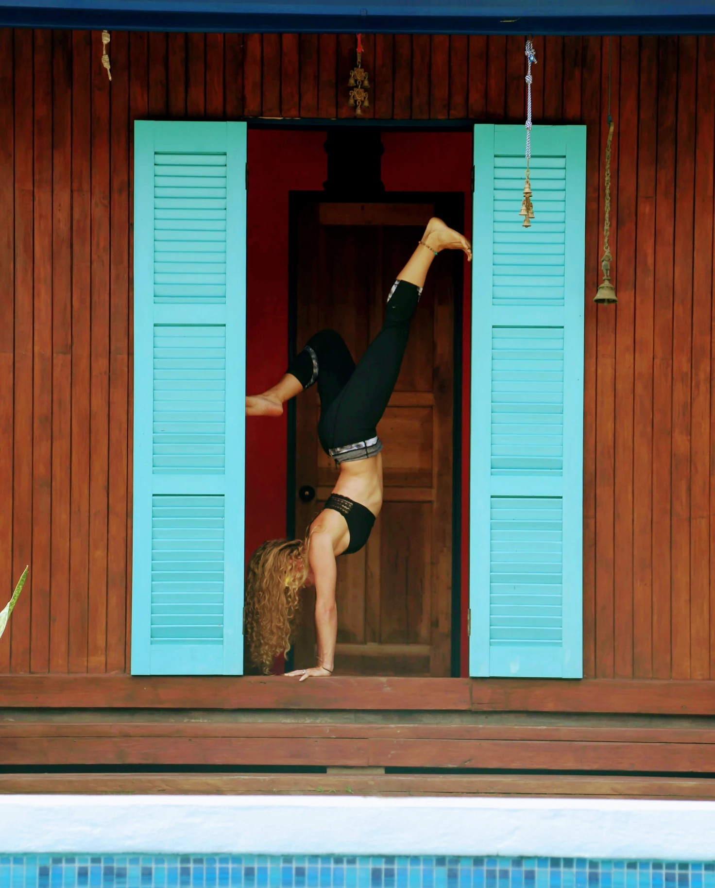 A yogi doing a headstand next to a blue door in Costa Rica. 
