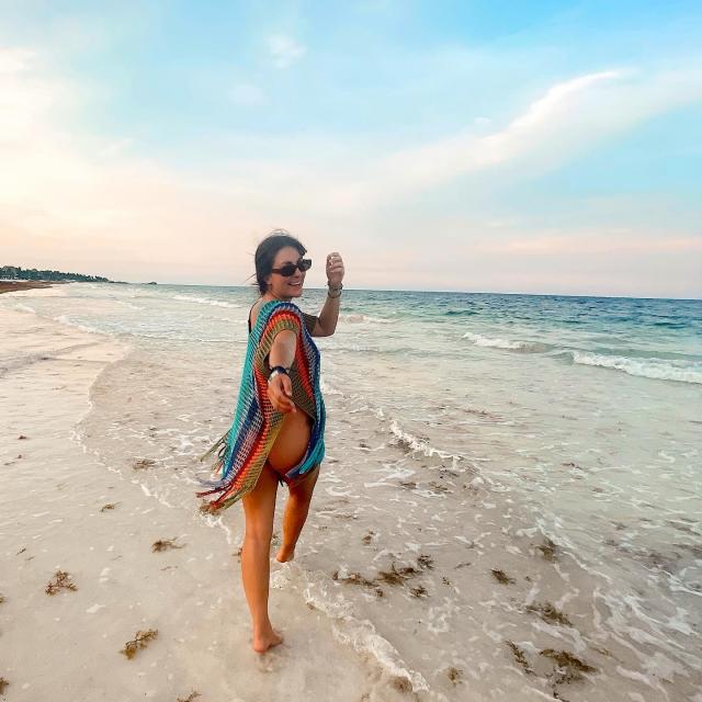 Fora Travel Agent Rachel Prestley standing on beach with ocean and blue skies