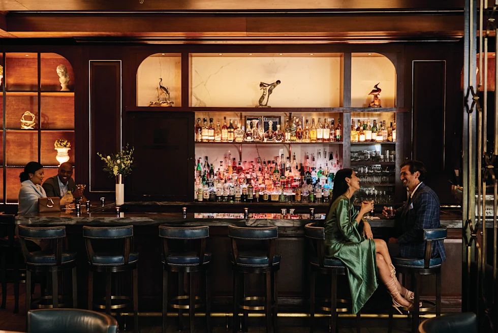people sitting a bar with dark leather chairs