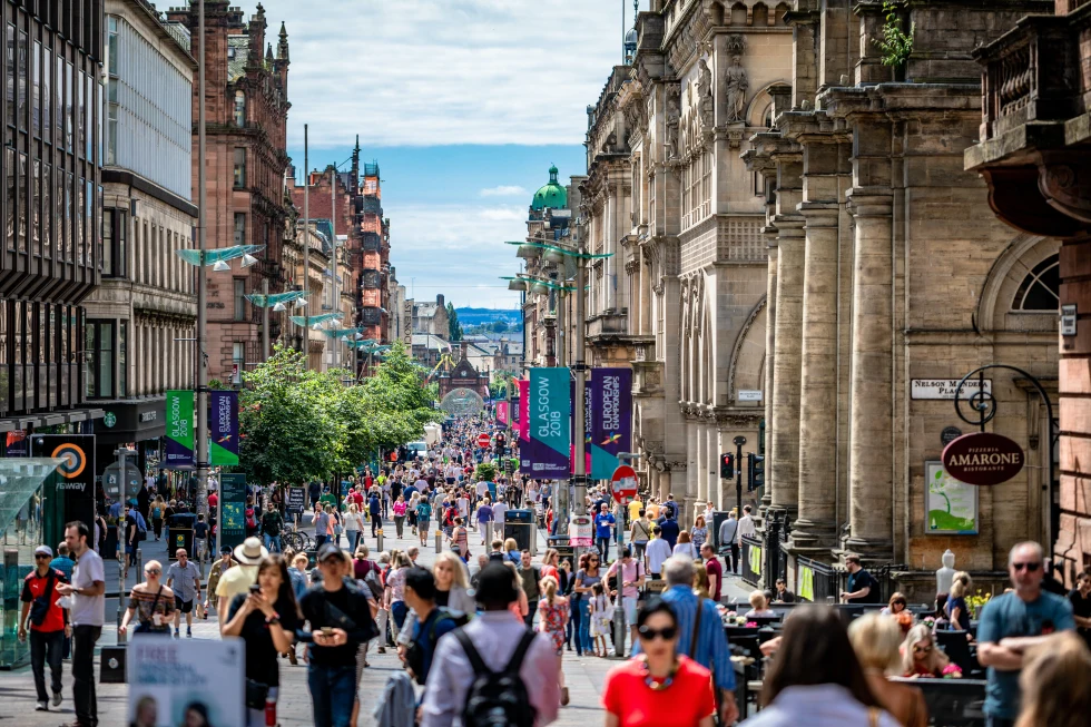Crowds of people walking on the street alongside buildings in Glasgow
