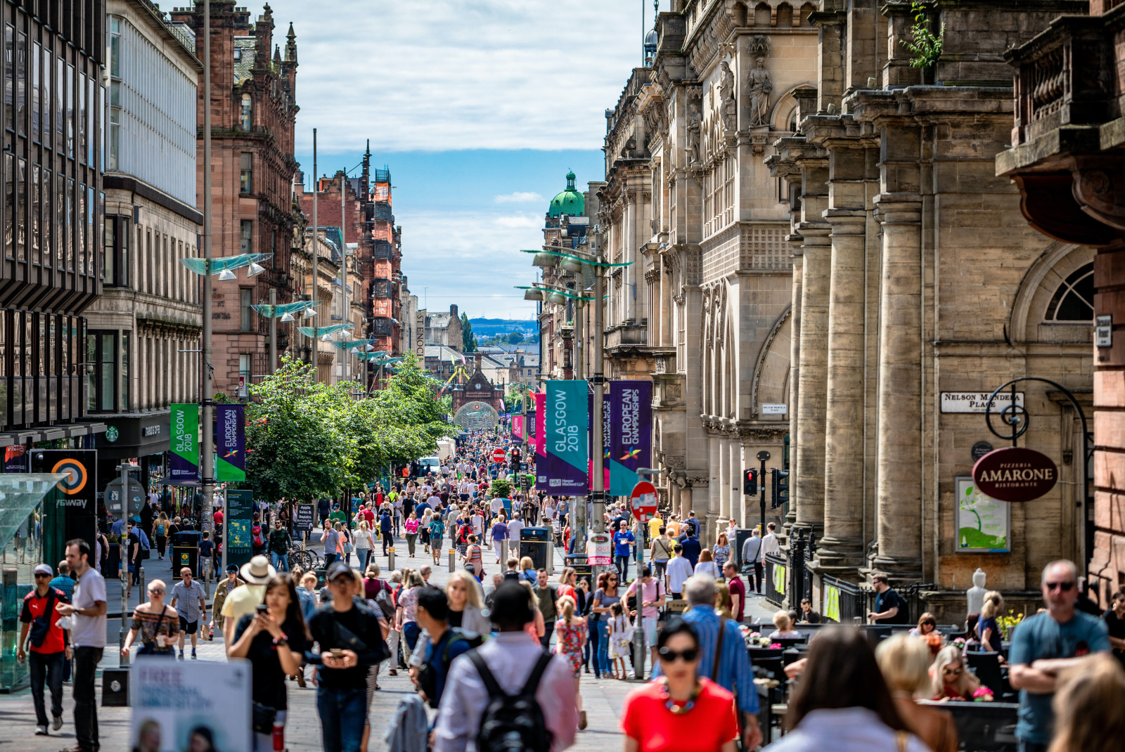 Crowds of people walking on the street alongside buildings in Glasgow