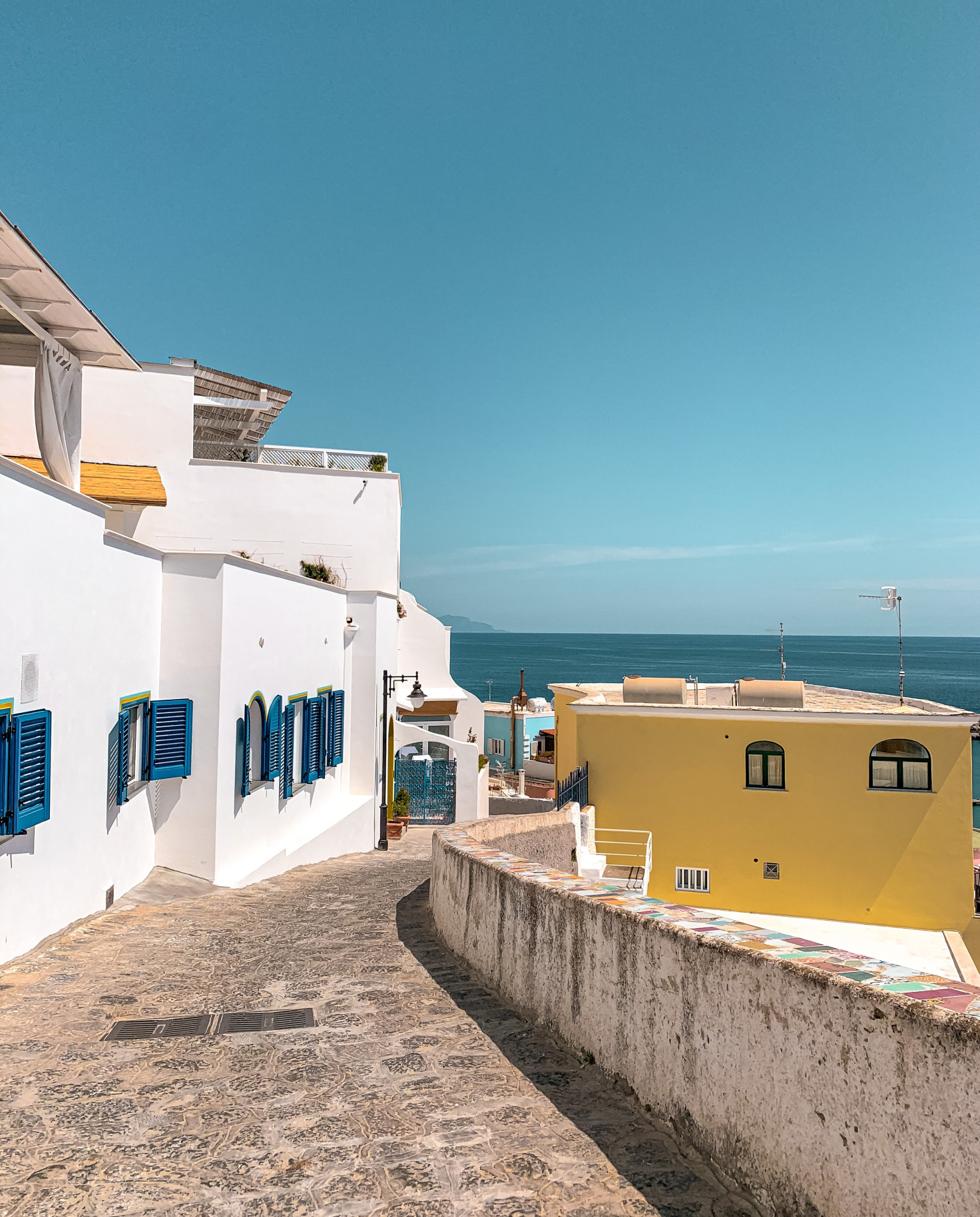 Ischia streets with whitewashed buildings and blue shutters. 