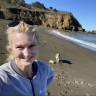 Fora travel agent Jody Holman standing on beach with dog and mountain