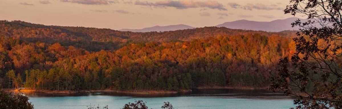 Carters Lake in Georgia surrounded by fall trees and mountains during sunset. 