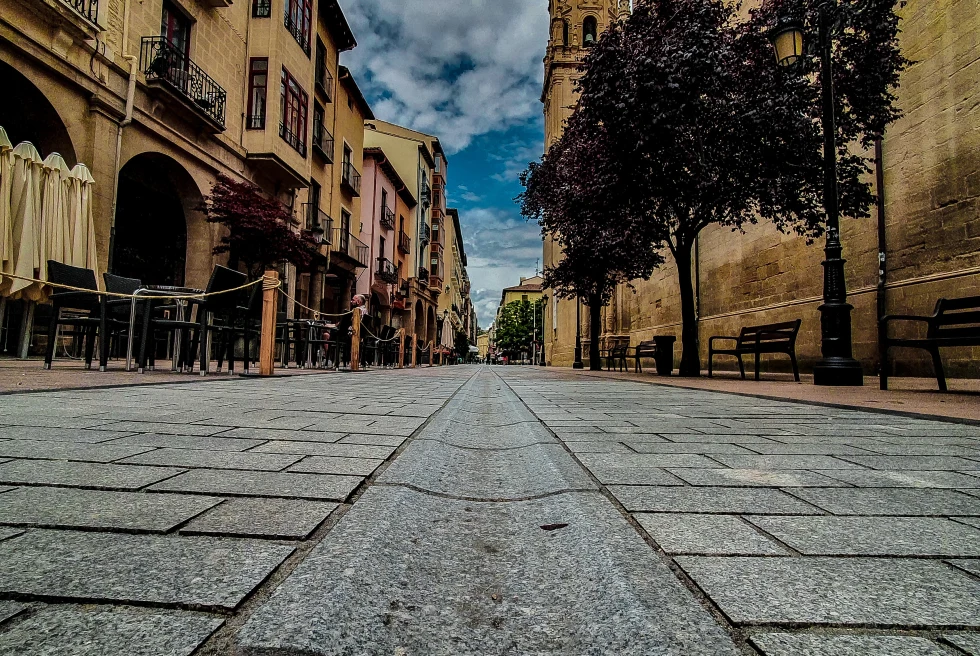 Street with tan buildings and cloudy skies during dusk