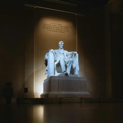 A statue of Abrahim Lincoln in a dimly lit room.