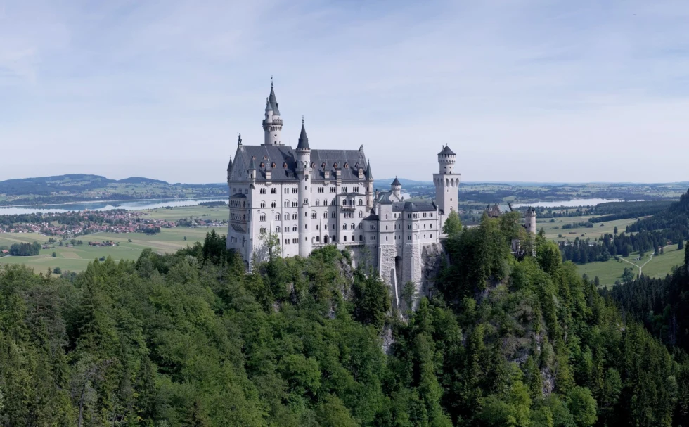 Neuschwanstein Castle surrounded by trees on a sunny day