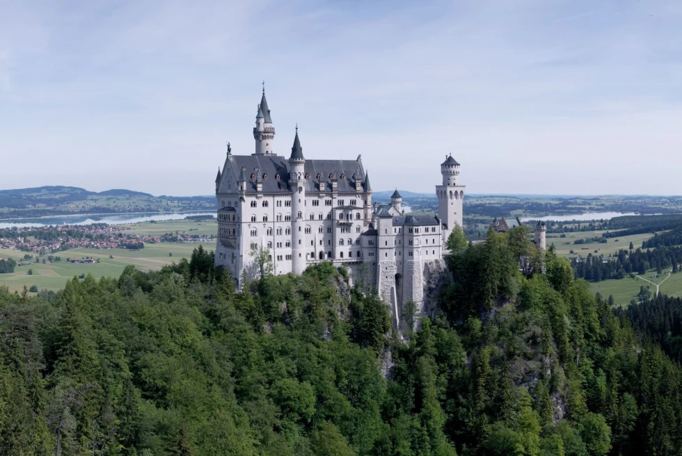 Neuschwanstein Castle surrounded by trees on a sunny day
