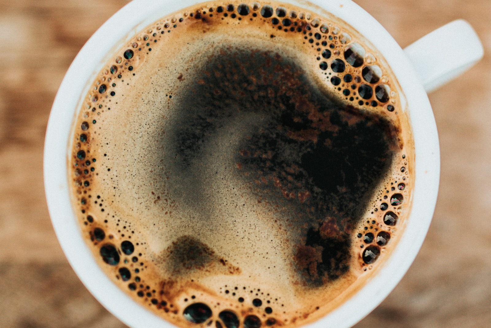 White mug filled with coffee on a wooden table