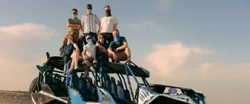 reizigers-poseren-bij-blauwe-buggy-in-zandduinen