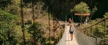 wandelaars-op-houten-hangbrug-in-bos