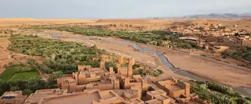 leemstenen-kasbah-aan-rivier-met-palmen