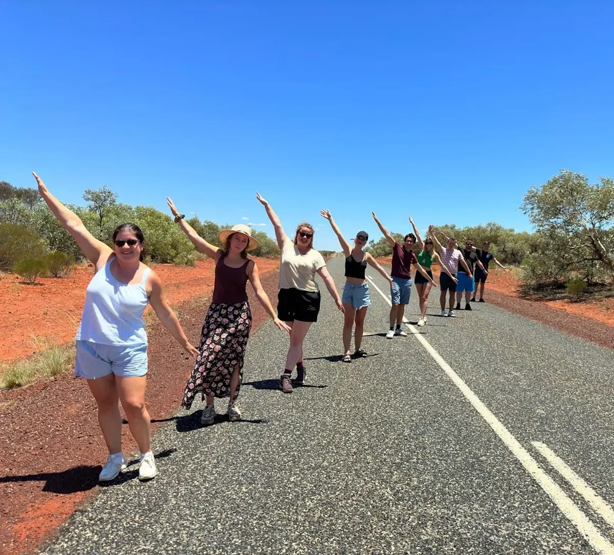 reizigers-met-opgeheven-armen-op-rode-weg &middot; amazing-australia