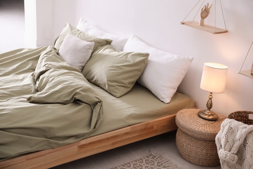 A comfortable bed with beige and white bedding.
