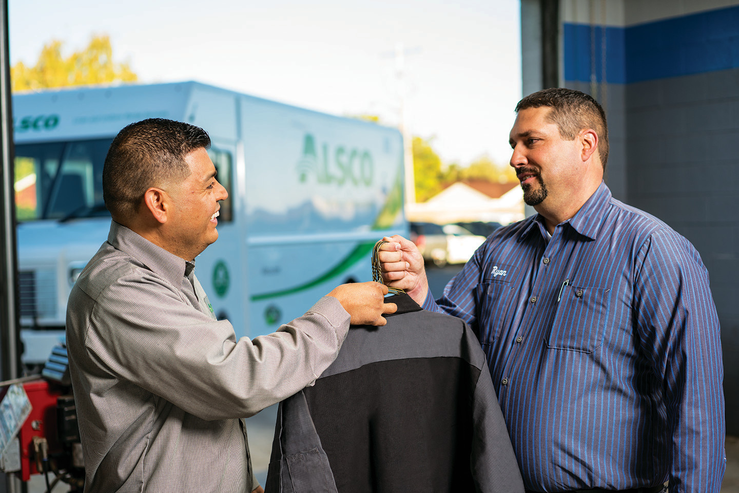 Alsco employee handing of clean uniform to customer.
