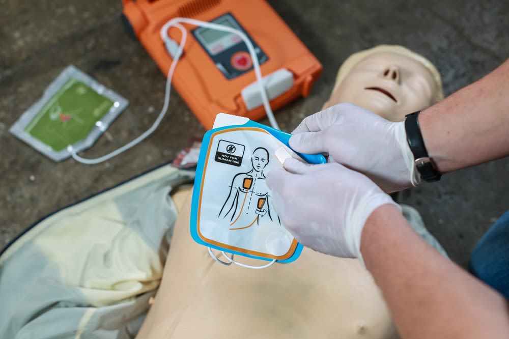 A person using a defibrillator on a training mannequin